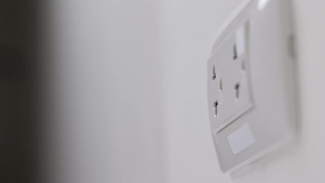 Close up male hand remove the Electric adapter smartphone or laptop plug. Electrical wires and power strips in the house