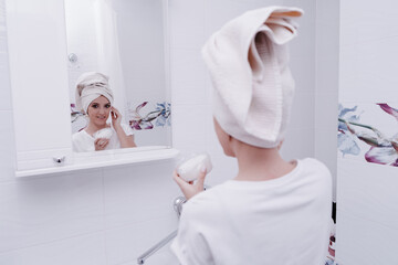 Portrait of a young woman with bad skin removing makeup with cleansing brush, device for household...