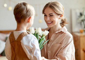 Happy mother with flowers hugging little son
