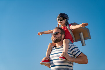 Father and son playing against blue summer sky background