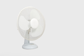 Ventilador eléctrico con hélice de tres palas sobre fondo gris con espacio de copia.