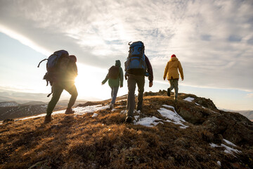 Hikers with backpacks walks in mountains at sunset