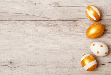 Colorful golden bright handmade painted easter eggs on a wood background.