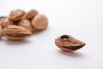 Rotten almonds against a pile of good nuts. A spoiled nut with a rotten kernel.