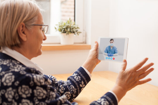 Elderly Caucasian Woman Talking To Young Female UK E-doctor Via Online Video Chat