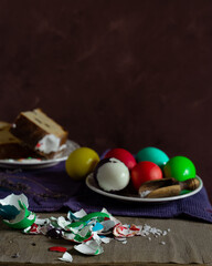 Still life with slices of Easter cake and colored eggs on rustic background