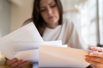 The manager can't handle the workload. A lot of documents and accounts in the woman's hands close up
