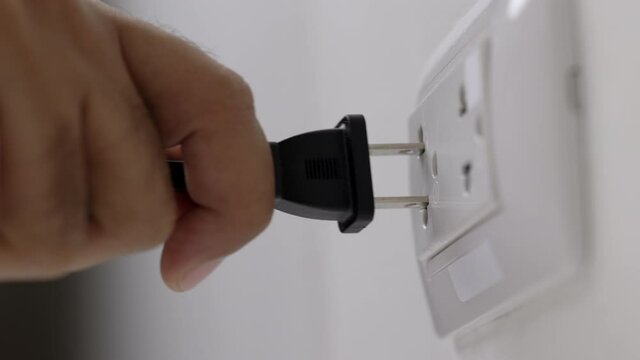 Hand holding Electric plug put on multiple socket. Electrical equipment, electrical wires and power strips in the house. Earth Hour saving electrical energy.