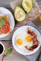Breakfast with fried eggs and bacon and sandwiches with guacamole sauce