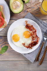 Breakfast with fried eggs and bacon and sandwiches with guacamole sauce