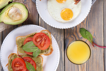 Breakfast with fried eggs and bacon and sandwiches with guacamole sauce