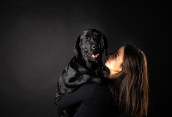 Obraz premium A girl holds a Labrador Retriever dog in her arms.