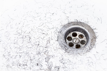 Dirty wash hand basin showing grungy drain with bits of hair