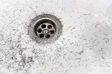 Dirty wash hand basin showing grungy drain with bits of hair