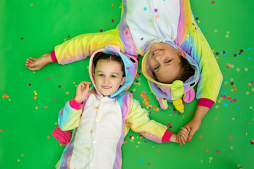 little girls in bright costumes lie on a green isolated background with a streamer in bright unicorn costumes. The concept of a holiday, Birthday and sales