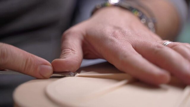 Luthier artisan wood worker using a chisel making a classical guitar ukulele 