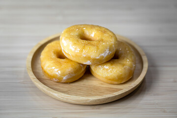Tasty original icing sugar donuts served on wooden plate. Bakery food close-up photo.