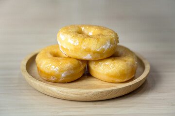 Tasty original icing sugar donuts served on wooden plate. Bakery food close-up photo.