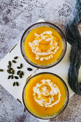 Soupe de courge au curry et baies roses dans un bol sur un fond couleur béton