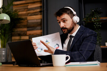 Young businessman working on laptop in his office. Handsome man having video call.