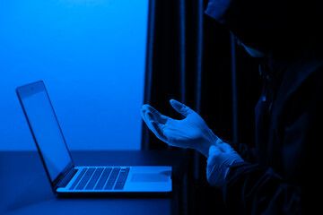 Scammer using laptop computer for hacking or steal data at night in office. Identity theft,...