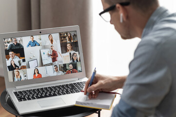 Brainstorm, online video meeting, virtual conference with multi ethnic coworkers, employee, colleagues. View over shoulder of a guy on a screen with webcam shots of diverse people