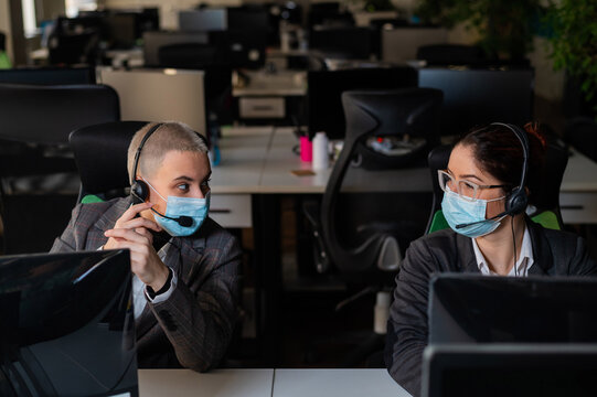 Two Women In Medical Masks Are Working In The Office. Female Call Center Operators