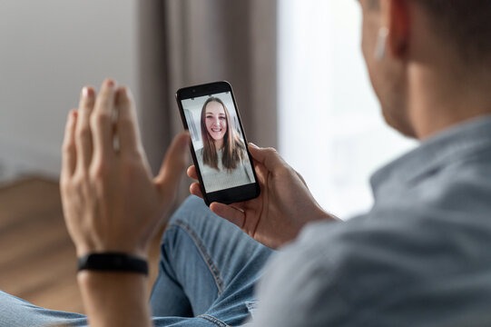 Video call on the smartphone. A young woman on the phone screen smiling, a guy is waving to her. App for video connection