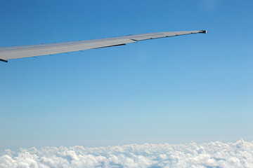 Window view on airplane wing with sky and clouds background