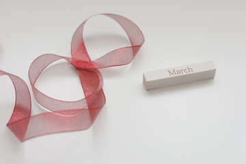Red ribbon and word MARCH on white background. 8 March, International Women's Day concept. 