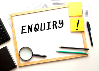 ENQUIRY text is written on a white office board. Work table with office supplies.