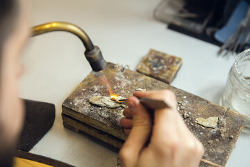 Heating. Close up hands of jeweller, goldsmiths making of golden ring with gemstone using professional tools. Craft production, precious and luxury jewel, hand made occupation. Workshop, artwork.