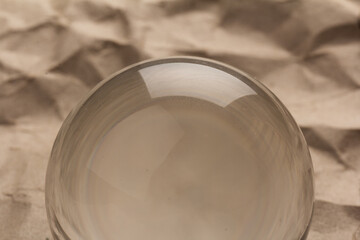 Fototapeta na wymiar Crystal, transparent ball, sphere on crumpled paper background.