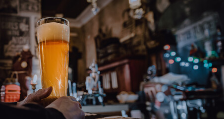 man holds a glass of beer in his hand at the bar or pub