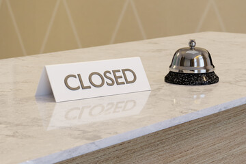 Closed sign on the white marble table of a hotel reception desk with a silver bell next to it