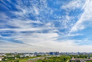 Obraz premium Panorama of the city under a high beautiful blue sky with light white curly clouds.