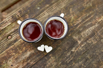 Enameled Two cups of tea in nature on wooden background, love, heart of marshmallow