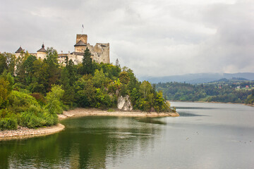 Fototapeta na wymiar Ancient castle Dunajec in Nedzice, Poland, Europe. Landscape with an old castle on a hill above the lake on a cloudy day.