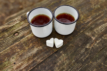 Enameled Two cups of tea in nature on wooden background, love, heart of marshmallow