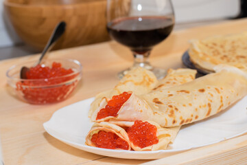 Red caviar with large white pancakes on a white plate. Traditional Russian cuisine on a holiday. Maslenitsa days.