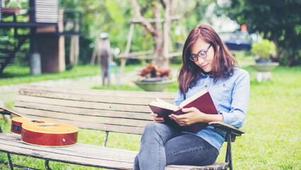 Woman reading book on park bench