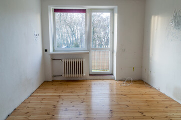 Old empty room with holes in wall and wooden floor.