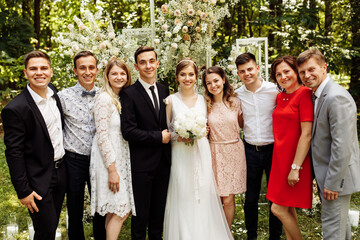 the newlyweds are photographed with family and friends. large group of people. A beautiful bride with a handsome groom is photographed with guests of different ages and nationalities against 