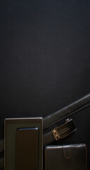 A belt with a golden buckle, a smartphone, a tablet and a notebook lie on a black background....