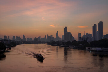 Beautiful landscape of business city with river ferry boat at twilight.