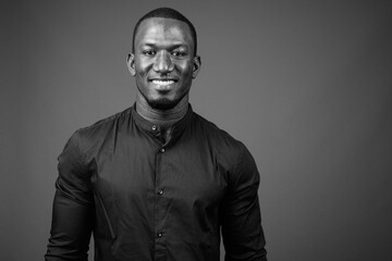 Handsome African businessman against brown background shot in black and white