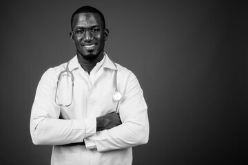 Handsome African man doctor wearing eyeglasses against brown background