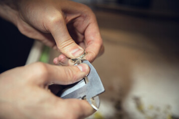 Craftsman. Close up hands of jeweller, goldsmiths making of silver ring with gemstone using professional tools. Craft production, precious and luxury jewel, hand made occupation. Workshop, artwork.