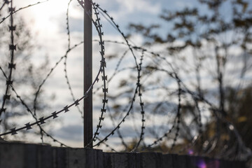 Barbed wire on the fence. The concept of prison, rescue, refugee, solitude.