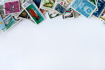Top border made of multicolored postage stamps collection from different countries on white...